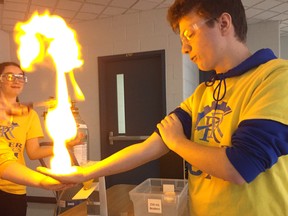 Evan Bayer, Grade 10 student at Beal, holds fire in his hand at the Beal science expo, as Amanda Morris, left, in Grade 10 and Sarah Arnold, Grade 12, look on