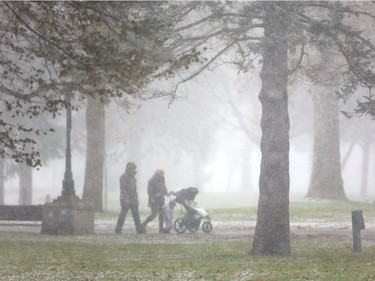 Jamieson Roberts and Nadia Petrasiunas of London walk though a short sudden snow flurry in Victoria Park with their daughter Rowan Roberts, 2 on Sunday November 19, 2017.  Mike Hensen/The London Free Press/Postmedia Network ORG XMIT: POS1711191545343695