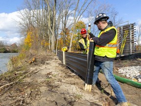 Evan Murphy and Craig Sim of J-Aar Excavating hammer in a silt fence to prevent dirt from their construction site from entering the Thames River. J-Aar is the lead contractor building two multi-use bridges and a pathway on the north side of the Thames River to close a gap between bike paths on Adelaide Street and Ross Parknear Richmond Street. (Mike Hensen/The London Free Press)