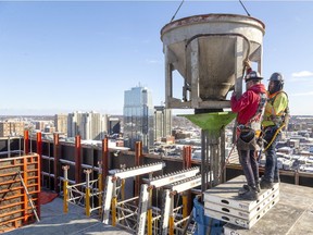 Anthony Soboczynski and Jordan Sargent of Ellis-Don handle a two-cubic-yard bucket as they pour concrete through a large funnel on Friday to fill one of eight support pillars that will hold up the new Old Oak apartment building being built at 515 Richmond St. across from St. Peter's Basilica. More Londoners are working, according to Statistics Canada October figures. (Mike Hensen/The London Free Press)