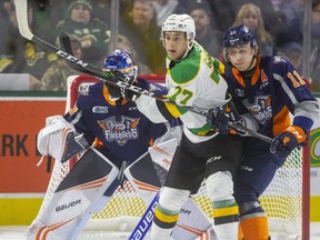 Matvey Guskov of the Knights tries to make some room in front of Flint goaltender Luke Cavallin while being checked by Dennis Busby of the Firebirds during the first period of their OHL game at Budweiser Gardens on Friday November 15, 2019.  Mike Hensen/The London Free Press/Postmedia Network