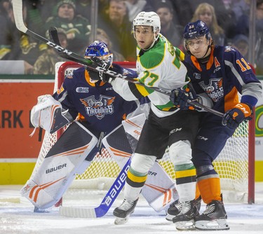 Matvey Guskov of the Knights tries to make some room in front of Flint goaltender Luke Cavallin while being checked by Dennis Busby of the Firebirds during the first period of their game at Budweiser Gardens on Friday November 15, 2019.  Mike Hensen/The London Free Press/Postmedia Network