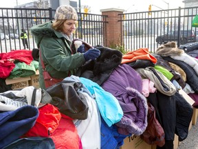 Lisa Walterson of London looks through a pile of women's coats at the Salvation Army Centre of Hope as London Homeless Helpers held their annual event on Sunday November 24, 2019. Mike Hensen/The London Free Press/Postmedia Network