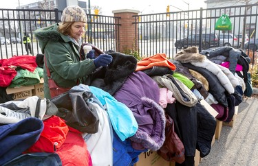 Lisa Walterson of London looks through a pile of women's coats at the Salvation Army Centre of Hope as London Homeless Helpers held their annual event on Sunday November 24, 2019. Mike Hensen/The London Free Press/Postmedia Network