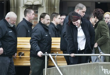 A grieving Stacey Sadowski, holds onto the railing outside St Theresa Church on February 6, 2004, as the casket containing her father Walter passes in the background. Walter Sadowski was one of 10-people killed in a plane crash off Pelee Island January 17, 2004.  At the right is his wife of 26-years, Theresa. (The Windsor Star-Dan Janisse)