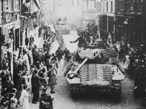 Dutch people line the street to greet Canadian soldiers as they parade down a street after the liberation of the Netherlands in 1945.