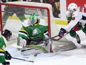 Windsor Spitfires Curtis Douglas, right, tries a wraparound against London Knights goaltender Dylan Myskiw and Avery Winslow, behind,  in the first period of OHL action at WFCU Centre in Windsor Sunday. (NICK BRANCACCIO/Windsor Star)