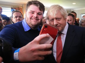 British Prime Minister Boris Johnson poses for a selfie with supporters on a visit to meet newly elected Conservative party MP for Sedgefield, Paul Howell at Sedgefield Cricket Club on December 14, 2019 in County Durham. (Lindsey Parnaby - WPA Pool/Getty Images)