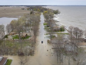 In this file photo from May 8, 2019, a truck slowly drives through flooded Cotterie Park Road in Leamington, as waves batter the shore of Lake Erie.