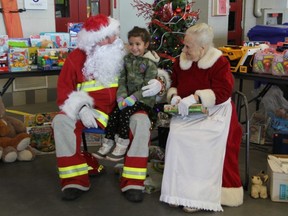 Kailyn Kumar, 5, sits with Firefighter Santa and Mrs. Claus at the London Fire Department headquarters Saturday Dec. 7. The emergency services open house collected toys for the Christmas sponsorship program at LifeSpin.