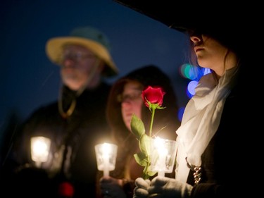 Bill Templeton, Megan Baxter and Jayme Archibald each hold a rose to be laid during the candlelight vigil at the Women's Monument in Victoria Park in London, Ont. on Tuesday December 6, 2016. (Mike Hensen/The London Free Press)