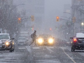 A pedestrian crosses Clarence Street at Dufferin Avenue as snow squalls hit downtown London, Ont. on Friday December 9, 2016. (File photo)