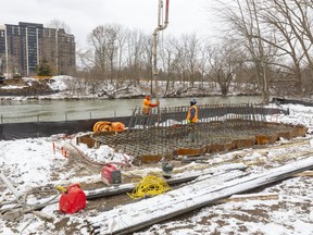 Hayman Construction workers pour concrete Thursday to form the base of a pier that will support one of the two bridges across the north branch of the Thames River, connecting the recreational Thames Valley Parkway from the North Athletic Fields on Adelaide Street to the section near Richmond Street. (Mike Hensen, The London Free Press)