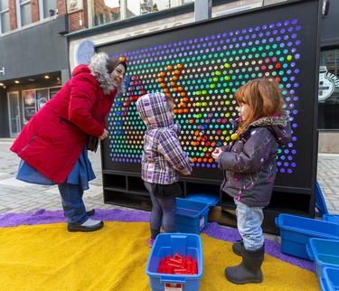 Wafae El Amraoui tells her daughter Israa, 3, to say "bonjour" to Harriet Sikora, also 3, as they play on the jumbo-sized Lite Brite on on London's Dundas Place flex street Friday. The new sections between Richmond and Wellington streets were closed for a celebration Friday afternoon. El Amraoui said her daughter speaks only French and Arabic as they had only arrived in Canada from Morocco a few months ago, but Harriet also knows French. (Mike Hensen/The London Free Press).