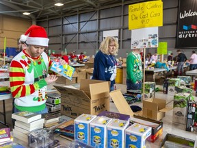 Backstage at the Salvation Army's Christmas hamper giveaway at the Western Fair Agriplex volunteer Derek Verzyl rocks an ugly sweater as he sorts gift books for boys and girls with various age groups separated.  (Mike Hensen/The London Free Press)