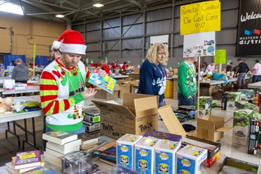 Backstage at the Salvation Army's Christmas hamper giveaway at the Western Fair Agriplex volunteer Derek Verzyl rocks an ugly sweater as he sorts gift books for boys and girls with various age groups separated.  Photograph taken on Monday December 16, 2019.  Mike Hensen/The London Free Press/Postmedia Network