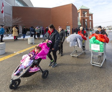 Natasha Hope and her daughter Autumn, 3, and friend Samantha Franssen leave the Salvation Army with two carts full of Christmas gifts and meals, pushed by volunteers Sherry Ditcher and Rob Di Valentin at the Western Fair Agriplex in London, Ont.  Photograph taken on Monday December 16, 2019.  Mike Hensen/The London Free Press/Postmedia Network