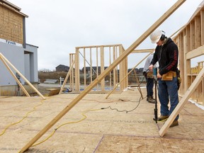 Jeff Hoornick (rear) and his son Garrett use drill guns to screw down a subfloor on a new home being built by Patrick Hazzard Custom Homes north of Sunningdale in London.  (Mike Hensen/The London Free Press)