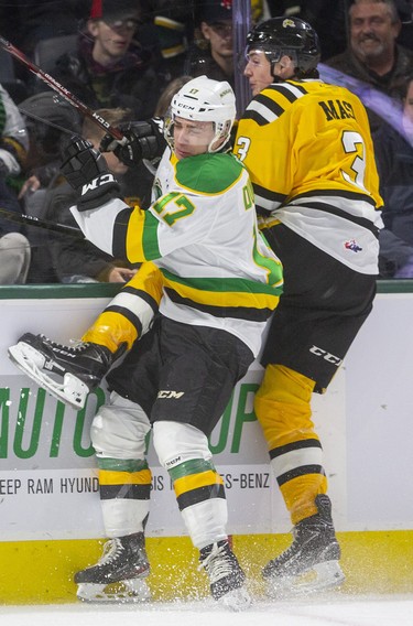 Nathan Dunkley of the Knights checks Sarnia's Ryan Mast behind the Sting net after a dump-in during their New Year's Eve game Tuesday afternoon at Budweiser Gardens in London. 
Mike Hensen/The London Free Press/Postmedia Network