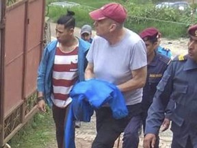 In this Monday, July 8, 2019 photo, Canadian aid worker Peter Dalglish, center wearing red cap, is brought to appear before the Kavre District Court in Nepal. Dalglish,convicted of sexually assaulting two children in Nepal, is set to argue he was the victim of a police conspiracy and unfair trial. (THE CANADIAN PRESS)