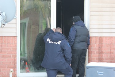 Police look into the rear entrace of a home at at 99 Kimberley Ave., where a fire damaged three townhouses on Tuesday night. A London man, 28, is charged with arson with disregard for human life. (DALE CARRUTHERS, The London Free Press)