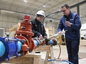 Instructor Corey Chambers shows Ontario’s minister of labour, Monte McNaughton, how to tap a water main serviced line at the LiUNA training facility in south London. McNughton was in the city Friday announcing close to $1 million in funding for pre-apprenticeship programs in the city. (Jonathan Juha/The London Free Press)