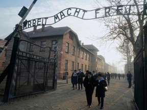Holocaust survivors walk below the gate with its inscription "Work sets you free" after a wreath laying at the death wall at the memorial site of the former German Nazi death camp Auschwitz during ceremonies to commemorate the 75th anniversary of the camp's liberation in Oswiecim, Poland, on January 27, 2020. (Photo by JANEK SKARZYNSKI / AFP)