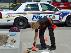 Det. Terri Jackson of London Police forensics investigates the scene of a stabbing in front of the Goodwill on Horton Street in London, Ontario on Tuesday July 25, 2017. (Free Press file photo)