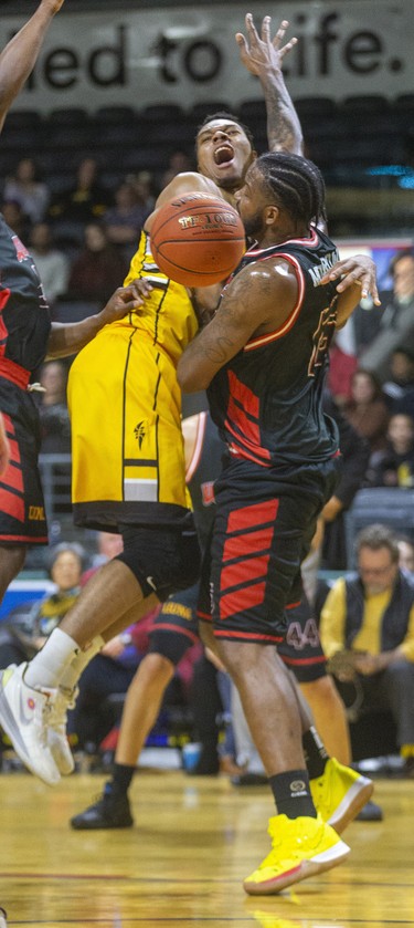 Mareik Isom of the London Lightning, stymied up close, passes behind the back of Windsor Express defender Sam Muldrow for an assist during the first half of their NBL game Thursday night at Budweiser Gardens in London. Mike Hensen/The London Free Press/Postmedia Network
