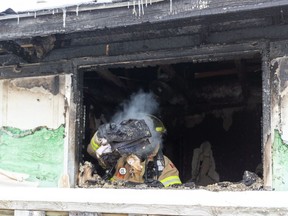 A London firefighter tosses smouldering clothing out of a window at 67 Patience Cr. in the White Oaks neighbourhood Monday after being called back to the scene of a fatal fire one day earlier. The Ontario Fire Marshal is investigating the blaze. (Mike Hensen/The London Free Press)