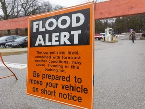 Warren Hayden, the parking operations coordinator for Western puts out barriers at the Talbot college parking lot next to the Thames River on campus in London, Ont.  Flooding is expected in low lying floodplain land in the city with peak levels expected on Sunday. Hayden said they were putting the signs out early so people knew not to leave their cars parked in the lots for the weekend. (Mike Hensen/The London Free Press)