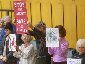 Nan Finlayson, left, who owns the home at 100 Stanley St. in London, holds a sign along with her supporters who want to stop city council from expropriating her land for road widening and rebuilding a train underpass. (Mike Hensen/The London Free Press)