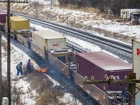 As a train moves through Tyendinaga, protestors light wooden pallets on fire next to the tracks while police look on from the other side. ALEX FILIPE