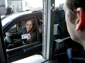 FILE: Michael Bosson, a Canada Customs employee shows his Nexus pass to Don Mounteer, a Canadian customs officer at the opening of the Nexus lane at the Windsor side of the Windsor-Detroit Tunnel.