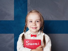 A girl holds her "Finland" book in front of the country's flag. Getty Images