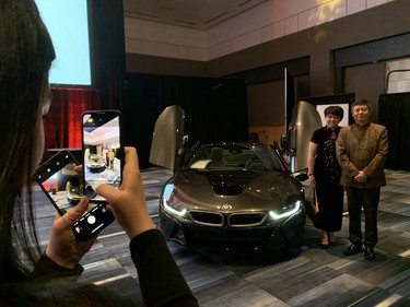 Cici Shi, left, snaps a photo of her parents Bruce and Nicole Shi, with a BMW Roadster. The luxury car was one of several on display at the 2020 Dragon Gala, an annual celebration for London's Chinese community. (Jennifer Bieman/The London Free Press)