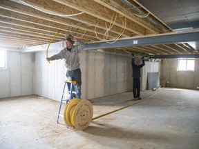 Tanner Dobson (left) and Ian McCallum install HVAC equipment in a home being built in the Woods Edge subdivision in Mt. Brydges. (Derek Ruttan/The London Free Press)