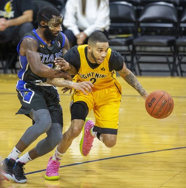 Damon Lynn of the Kitchener-Waterloo Titans corals Xavier Moon of the London Lightning during their National Basketball League of Canada game at Budweiser Gardens in London on Thursday. (Derek Ruttan/The London Free Press)