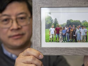 Dr. Charles Xu is a professor and director of Industrial Bioproduct Laboratory at Western University's  Institute for Chemicals and Fuels from Alternative Resource in London, Ont. on Saturday February 8, 2020. He holding a group photo of people who work and study at ICFAR. At left is Milad Nahavandi, one of the four Western students that died when Iran shot down a passenger jet last month. (Derek Ruttan/The London Free Press)