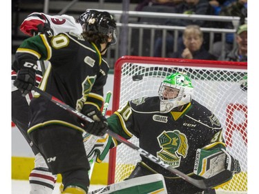 Antonio Stranges of the London Knights and Danny Zhilkin of the Guelph Storm watch  a high shot from the Guelph point that nearly bounces in over Brett Brochu in the net during the first period of their game at Budweiser Gardens in London, Ont.  Tuesday Feb. 11, 2020.  Mike Hensen/The London Free Press