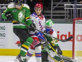 Knights forward Connor McMichael gets hit by the puck as he checks Kitchener's Mike Petizian in front of Brett Brochu during the first period of their Friday night game at Budweiser Gardens in London. Photograph taken on Friday February 14, 2020. Mike Hensen/The London Free Press/Postmedia Network