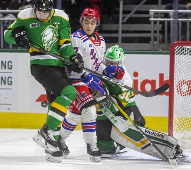 Knights forward Connor McMichael gets hit by the puck as he checks Kitchener's Mike Petizian in front of Brett Brochu during the first period of their Friday night game at Budweiser Gardens in London. Photograph taken on Friday February 14, 2020. Mike Hensen/The London Free Press/Postmedia Network