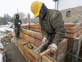 Al Riordan (right) hammers in a board holding the top of a foundation form straight with Ryan Riczu also of Concrete Forming running a straight line for another new house going up between Fanshawe Park Road and Sunningdale near Hyde Park Road in London, Ont.  (Mike Hensen/The London Free Press)