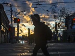 A pedestrian is silhouetted against the sunset while crossing Gerrard Street East at Broadview Avenue in Toronto on Tuesday February 18, 2020. Ernest Doroszuk/Toronto Sun/Postmedia