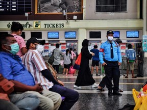 People, wearing facemasks amid concerns over the spread of the COVID-19 novel coronavirus, wait inside the terminal at Hua Lampong railway station in Bangkok on March 9, 2020. (Photo by Lillian SUWANRUMPHA / AFP)
