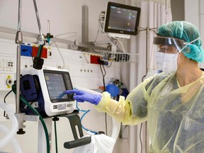 This picture taken on March 16, 2020 during a press presentation of the hospitalisation service for future patients with coronavirus at Samson Assuta Ashdod University Hospital in the southern Israeli city of Ashdod, shows the director of the epidemics service Dr Karina Glick checking a medical ventilator control panel at a ward, while wearing protective clothing. - As of March 16, Israel has 255 confirmed cases of coronavirus with no fatalities but tens of thousands in home-quarantine. Authorities have banned gatherings of more than 10 people and ordered schools, universities, restaurants and cafes to close, among other measures. (Photo by JACK GUEZ / AFP)