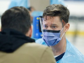 A medical worker assesses someone portraying the role of a patient as hospital staff prepare to receive people for coronavirus screening at a temporary assessment center at the Brewer hockey arena in Ottawa, Ontario, Canada March 13, 2020.  (REUTERS/Patrick Doyle)