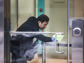 A man cleans the door to the Toronto building where a person diagnosed with the coronavirus attended ESL classes. (Ernest Doroszuk/Postmedia Network)