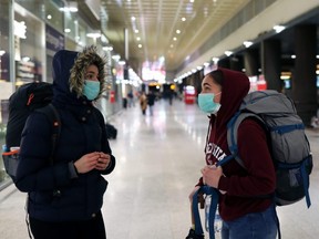 Two Portuguese passengers wearing protective masks were trapped in Venice at the establishment of a quarantine are seen at the Venice Santa Lucia train station trying to understand how to leave the city on Sunday, March 8, 2020 in Venice, Italy.