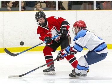 Medway Cowboys player Ava Lewis, left, and Lucas Viking Keira Min battle for the puck during their TRVA Central girls hockey championship game at Stronach Arena in London on Thursday. (Derek Ruttan/The London Free Press)